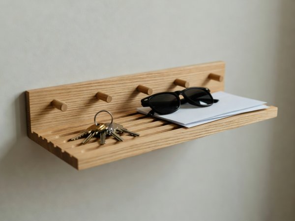 Close view of an ash peg rail with a slotted wooden valet tray holding keys, sunglasses and incoming letters